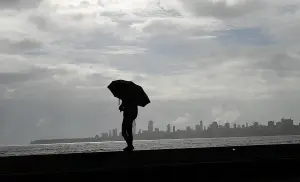 A person standing at the frontier shoreline holding an umbrella at the marine drive.